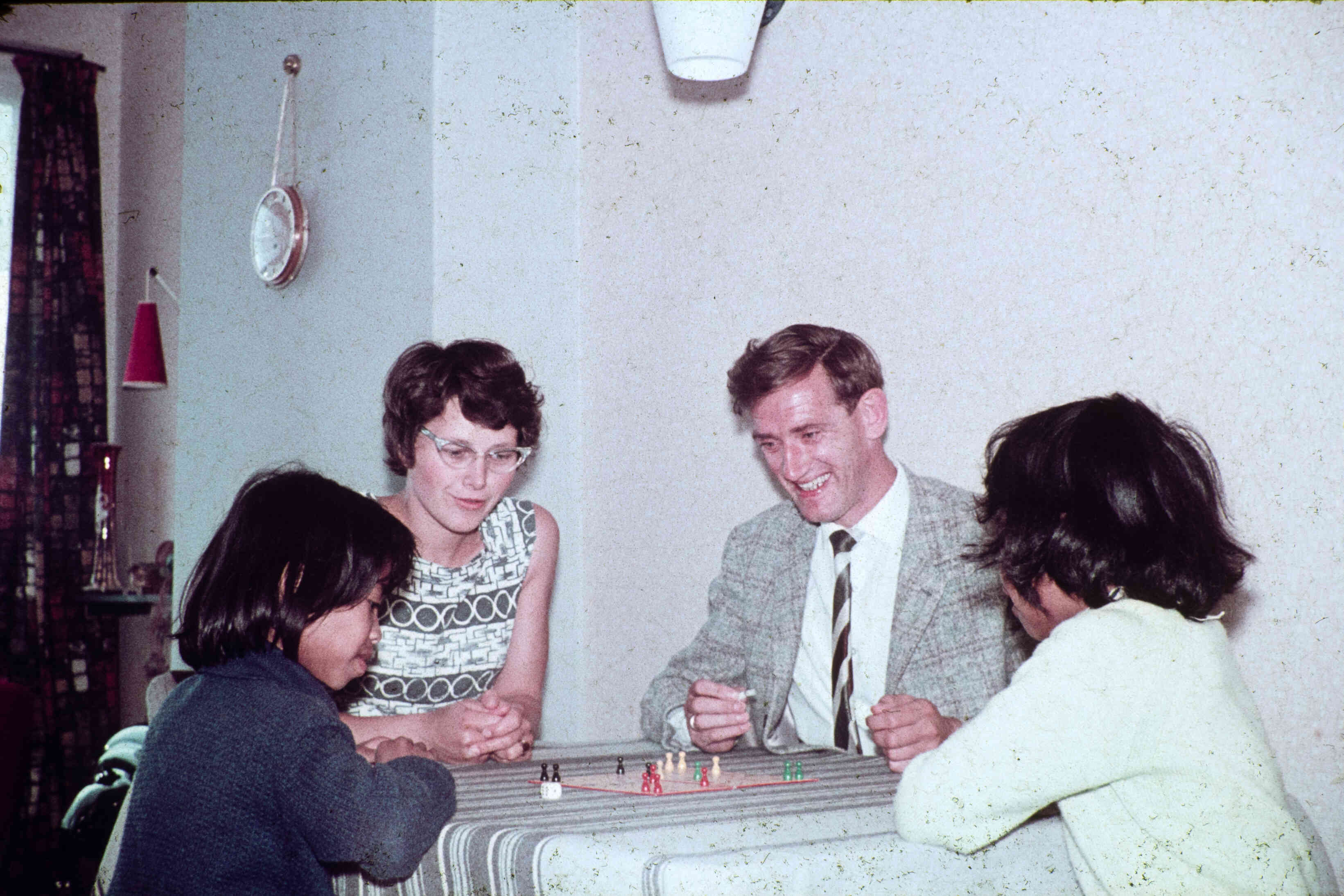 Oude foto van mensen die mens erger je niet spelen, Ambonese kinderen logeren bij Friese pleegouders, rond 1960